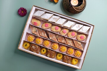 Indian assorted Diwali sweets or mithai box with diya and flowers. Festive gift idea. Kaju katli,...