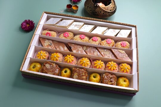 Indian assorted Diwali sweets or mithai box with diya and flowers. Festive gift idea. Kaju katli, dry fruits peda, barfi, cashew nut barfi, marzipan, khoya cakes. christmas box. copy space.