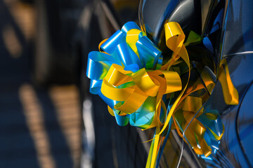 Car decorated with yellow and blue ribbons . Artificial flower made by ribbons , wedding decoration