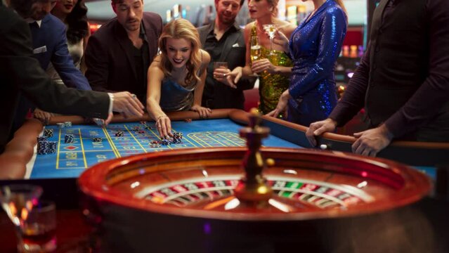 Slow Motion Footage of a Spinning Roulette Wheel. Focus Switching to Female and Male Guests Placing Risky Bets while Playing Roulette. Crowd Celebrating a Positive Outcome and Cheering the Winner