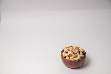 Pistachios or salt Pista on white bowl with white background, Pistachios or salt Pista scattered on the white background in a black bowl or wooden bowl. A raw salted pistachios consumed for food