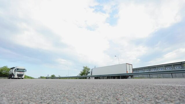 The camera shoots the road from a lower angle. Shooting a highway from a low angle. Cars are driving along the highway past the camera.