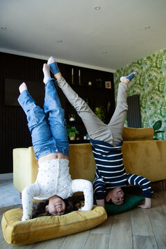 Brother and sister doing handstands in the living room smiling