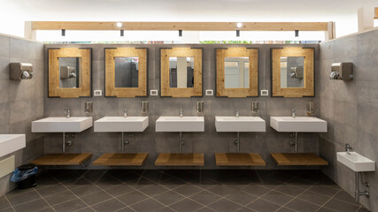 Public bathroom with five sinks, mirrors and soap dispensers. Modern and simple.