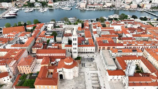 Aerial video of the famous city of Zadar in Croatia, old town with St. Donat church and Cathedral of St. Anastasia bell tower surrounded by turquoise Adriatic sea.
