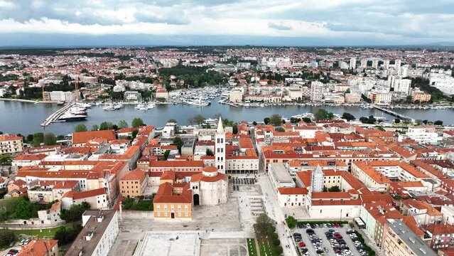 Aerial video of the famous city of Zadar in Croatia, old town with St. Donat church and Cathedral of St. Anastasia bell tower surrounded by turquoise Adriatic sea.