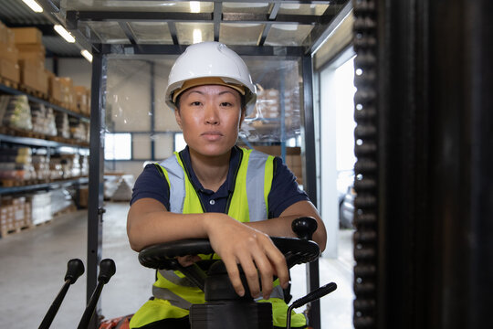Portrait of employee in distribution warehouse driving a forklift truck