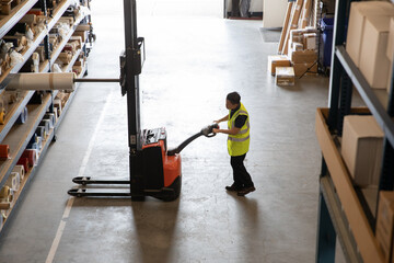 Worker in a warehouse using machinery to lift product