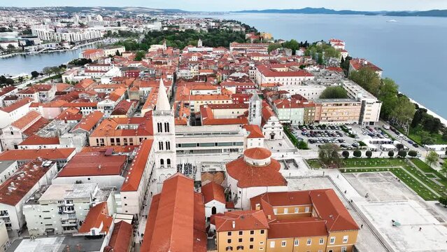 Aerial video of the famous city of Zadar in Croatia, old town with St. Donat church and Cathedral of St. Anastasia bell tower surrounded by turquoise Adriatic sea.