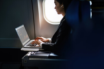 Successful Asian business woman, Business woman working in airplane cabin during flight on laptop...