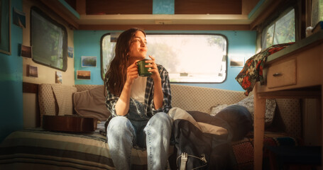 Attractive Young Female Drinking Tea or Coffee in Her Cozy Motorhome. Adventurous Woman Travelling...