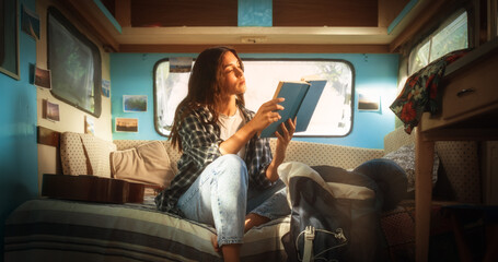 Young Adult Female Enjoying Her Time in a Motorhome, Relaxing and Reading an Adventure Book Story. Beautiful Girl Camping in a Caravan, Having a Journey to Rediscover Her True Self - obrazy, fototapety, plakaty