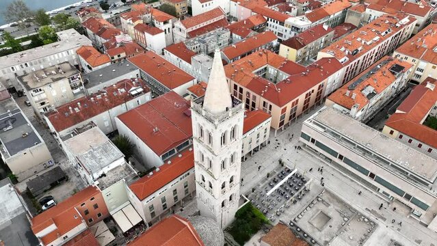 Aerial video of the famous city of Zadar in Croatia, old town with St. Donat church and Cathedral of St. Anastasia bell tower surrounded by turquoise Adriatic sea.