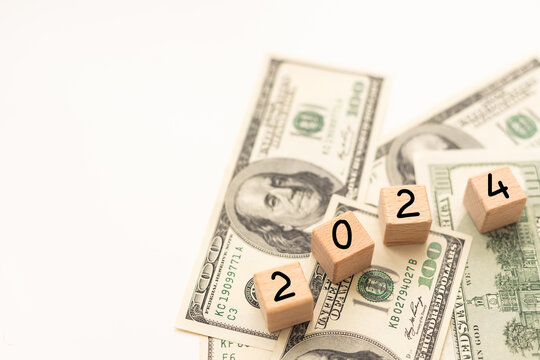 2024 inscription on wooden cubes on the texture of us dollars and euro banknotes