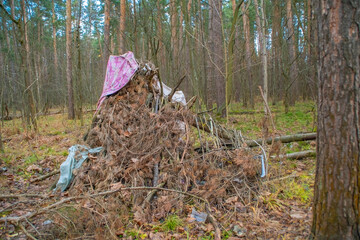 A primitive hut made of branches and rags in the park.