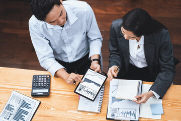 Top view multiracial analyst team use BI dashboard data to analyze financial report on meeting table. Group of diverse business people utilize data analysis by FIntech for business decision. Concord