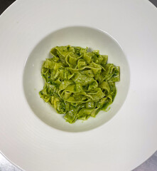 Close up top view of a pasta dish with pesto sauce in a restaurant kitchen - 681480523