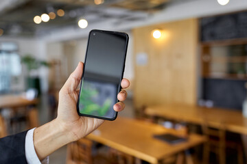 カフェでスマートフォンを使うビジネスマンの手元