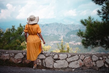 Vibrant yellow-dressed woman captivated by mountain vistas