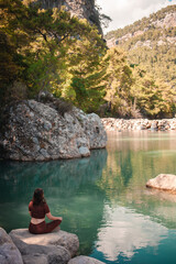 Woman enjoying tranquility on the background of a mountain lake while traveling in Turkey.