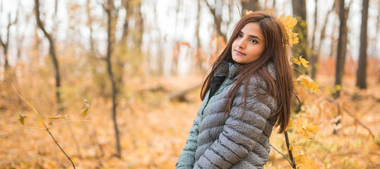 Close-up portrait of diversity young beautiful confident Indian Asian woman in fall outdoor copy space banner mockup. Happy and natural smiling female. Generation z and gen z youth concept