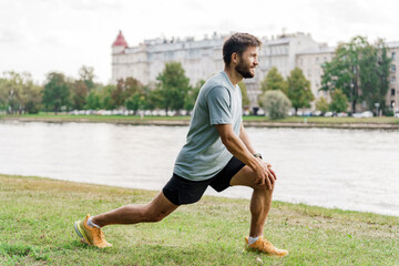 Fototapeta premium Body warm-up A running man is a sporty, slender young man in a T-shirt, shorts. Interval training for running alone in the park.
