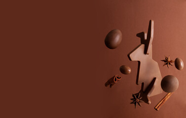 Chocolate Easter bunny levitates with candy Easter eggs on a brown background