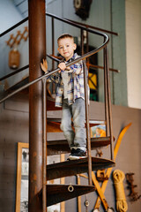 Funny little boy in plaid shirt and jeans in the interior of a country house. 