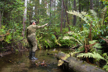 Fototapeta premium a fisherman with a spinning rod throws a lure on a forest river