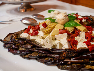 An Mediterranean plate featuring feta cheese, bell peppers, artichokes, mushrooms, and aubergines