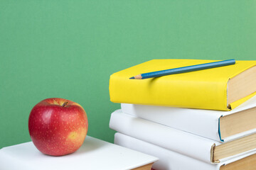Books stacking. Books on wooden table and green background. Back to school. Copy space for ad text.