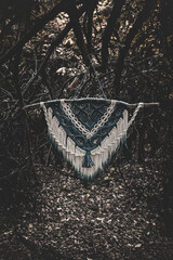 Panel of blue and white macrame on a decorative branch in nature