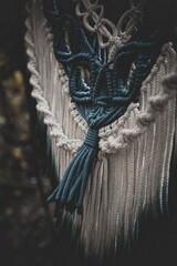 Panel of blue and white macrame on a decorative branch in nature