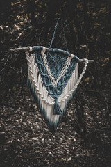 Panel of blue and white macrame on a decorative branch in nature