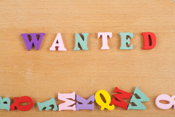 WANTED word on wooden background composed from colorful abc alphabet block wooden letters, copy...