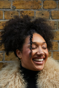 Portrait of a biracial girl with curly afro hair and a tooth gem, wearing a furry coat. Concept of gen z, fashion and self expression