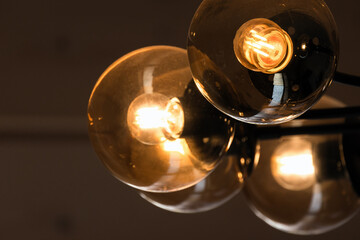 Tungsten lamps glow in round glass lampshades, modern chandelier