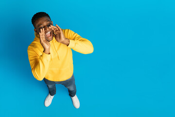 Handsome black guy shouting towards copy space, high angle view