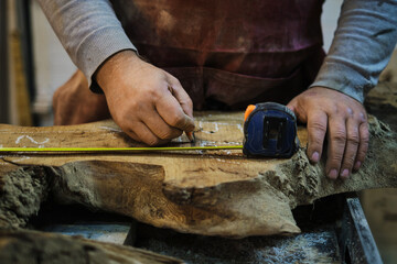 Marking out cuts on a wood slab, accuracy focused. Demonstrates the skill behind custom woodworking in demand.