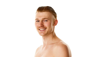 Young attractive man with bared shoulders looking at camera and smiling with teeth against white studio background.