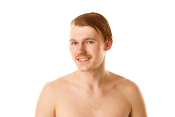 Portrait of smiling, cheerful, naked man with red and wet hair looking at camera against white studio background.