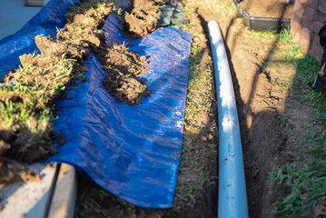 Blue tarp, black mixing tub container with dirt, underground PVC pipe buried in trench...