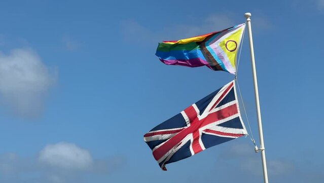 LGBT and UK flags flutter against the blue sky