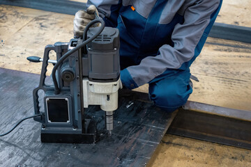 Magnetic drilling machine. Construction equipment in hands of repairman. Drilling holes in metal...