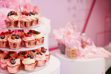 A plate of cupcakes decorated with white and pink cream with berries. 