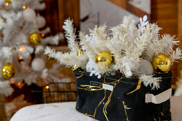 Details of the Christmas interior. Textile basket with a Christmas composition of white spruce twigs, snowflakes, balls.