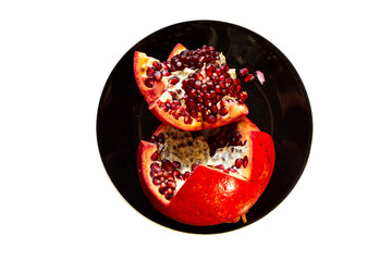 Top view of fresh ripe sweet pomegranate in black ceramic dish isolated on white background