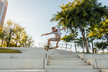 Active skater jumping on skateboard over stairs in park