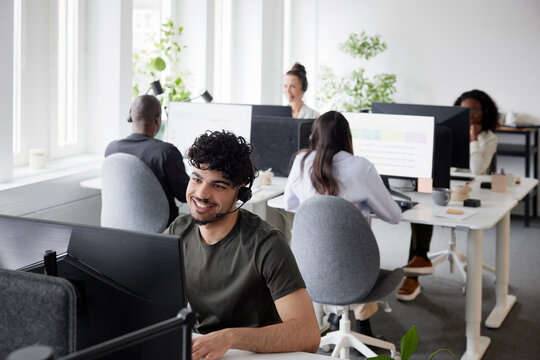 Man wearing headset using desktop PC in office