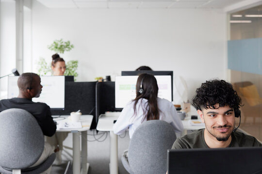 Man wearing headset using desktop PC in office